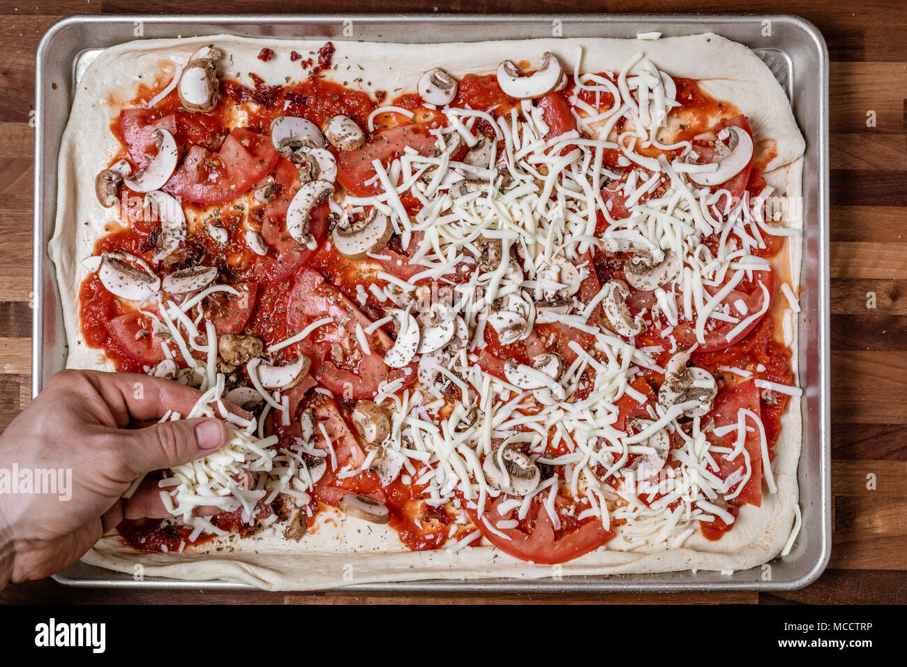 Mann Verbreitung shredded Cheddar Käse, hausgemachte Pizza Stockfoto