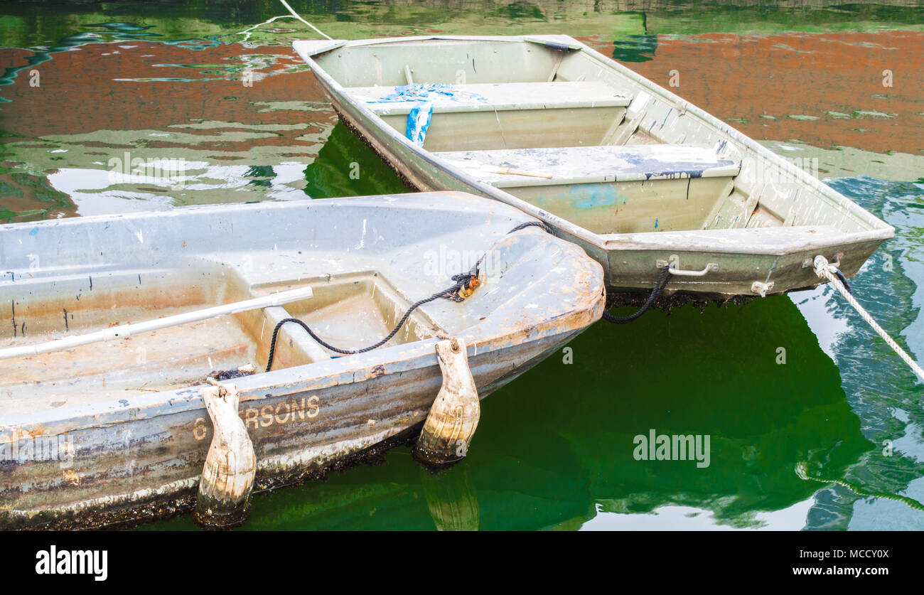 2 Leere vintage Ruderboote mit Farbe Flecken zusammen in Baltimore Inner Harbor gebunden mit bunten Spiegelungen im Wasser bedeckt Stockfoto