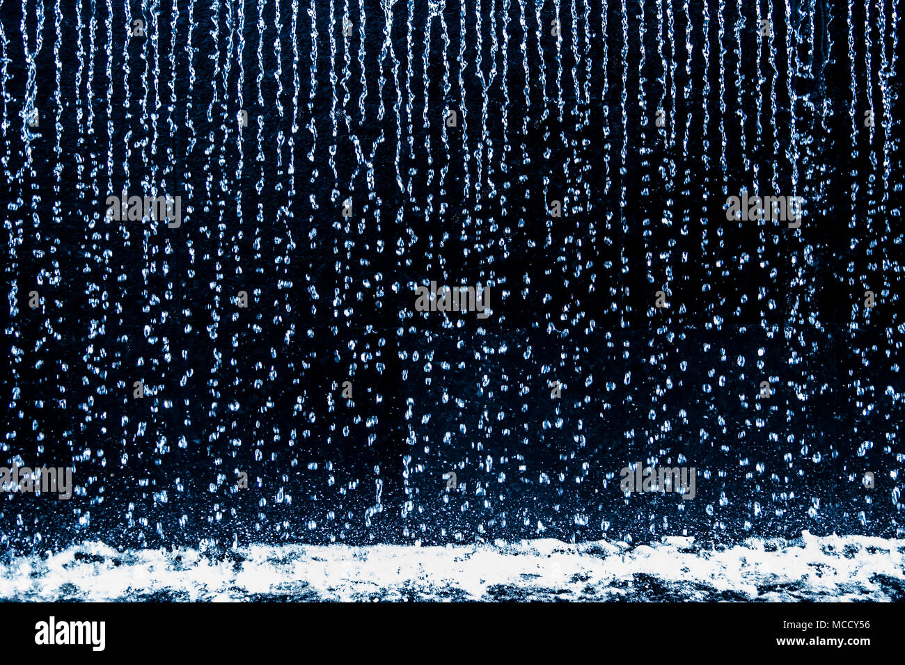 Regen Tropfen nach unten kontinuierlich laufenden auf schwarzem Hintergrund. Stockfoto