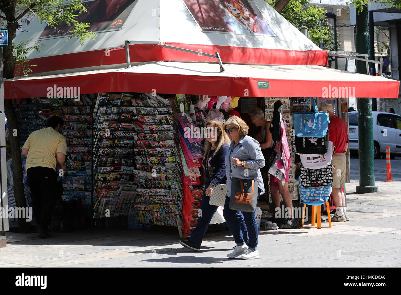 Athen, Griechenland. 14 Apr, 2018. Menschen gehen vorbei an einer Straße Kiosk in Athen, Griechenland, am 14. April 2018. Seit über einem Jahrhundert, Griechen und Touristen können durch Straße Kiosk in Ihrer Nachbarschaft 24 Stunden am Tag, 365 Tage im Jahr Zeitungen, Batterien oder ein paar Snacks und eine Flasche Wasser zu holen. Allerdings ist die Kioske, oder PERIPTERA, die traditionelle kleine Geschäfte, die an den Ecken des zentralen Straßen oder Plätzen in ganz Griechenland gefunden werden können, haben auch die Opfer der acht Jahre Schuldenkrise. Credit: Marios Lolos/Xinhua/Alamy leben Nachrichten Stockfoto
