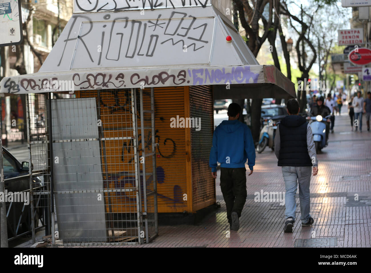 Athen, Griechenland. 14 Apr, 2018. Menschen gehen vorbei an einer geschlossenen Straße Kiosk in Athen, Griechenland, am 14. April 2018. Seit über einem Jahrhundert, Griechen und Touristen können durch Straße Kiosk in Ihrer Nachbarschaft 24 Stunden am Tag, 365 Tage im Jahr Zeitungen, Batterien oder ein paar Snacks und eine Flasche Wasser zu holen. Allerdings ist die Kioske, oder PERIPTERA, die traditionelle kleine Geschäfte, die an den Ecken des zentralen Straßen oder Plätzen in ganz Griechenland gefunden werden können, haben auch die Opfer der acht Jahre Schuldenkrise. Credit: Marios Lolos/Xinhua/Alamy leben Nachrichten Stockfoto