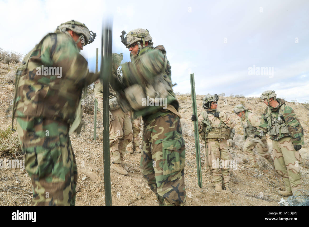 Us-Soldaten des 3.Kavallerie Regiments anlage Pfähle in den Boden mit einem streikposten pounder zugewiesen, um faltenbalg Kabel während der entscheidenden Aktion Rotation 18-04 am National Training Center in Fort Irwin, Calif., Feb 13, 2018. National Training Center entscheidende Maßnahmen Rotation 18-04 ist entworfen, um zu prüfen, dass die Fähigkeiten von 3 Cavalry Regiment gegen ähnlich ausgestatteten gegen die Bedrohung. (U.S. Armee Foto von SPC. Dana Clarke, Operations, National Training Center) Stockfoto