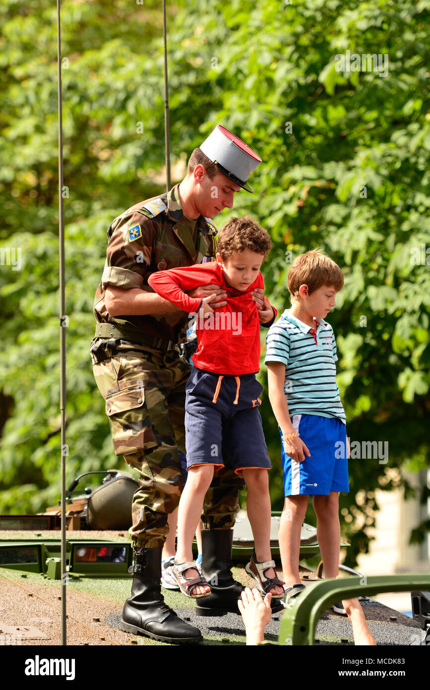 Ein französischer Soldat hilft einem Kind aus der Spitze eines militärischen Tank während der Bastille Day Parade in Paris ankommen. Stockfoto