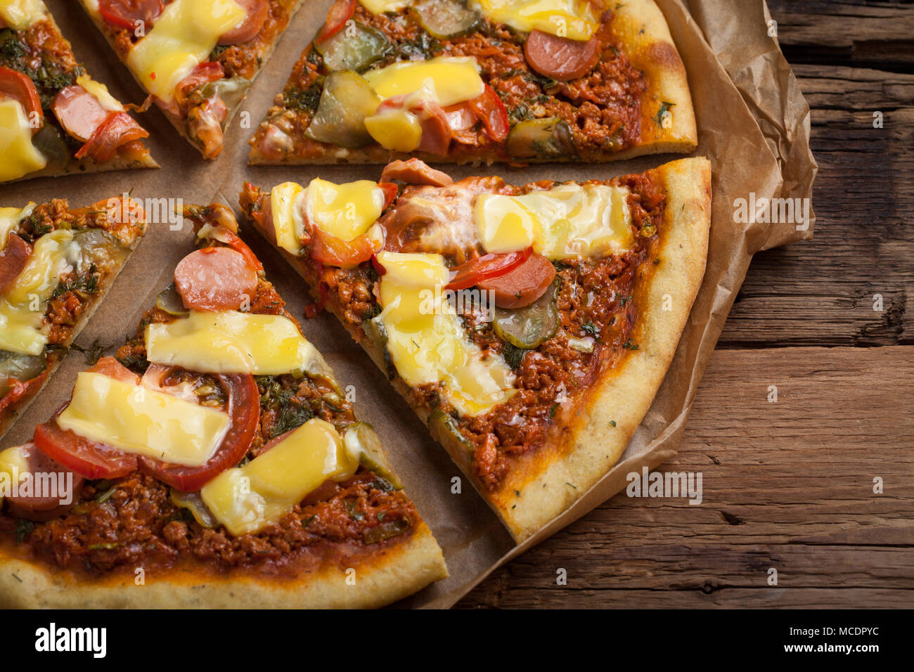 Hausgemachte vegane Pizza mit Tomaten, Gurken, vegane Wurst und Käse auf einem alten Holztisch. Ansicht von oben. Stockfoto