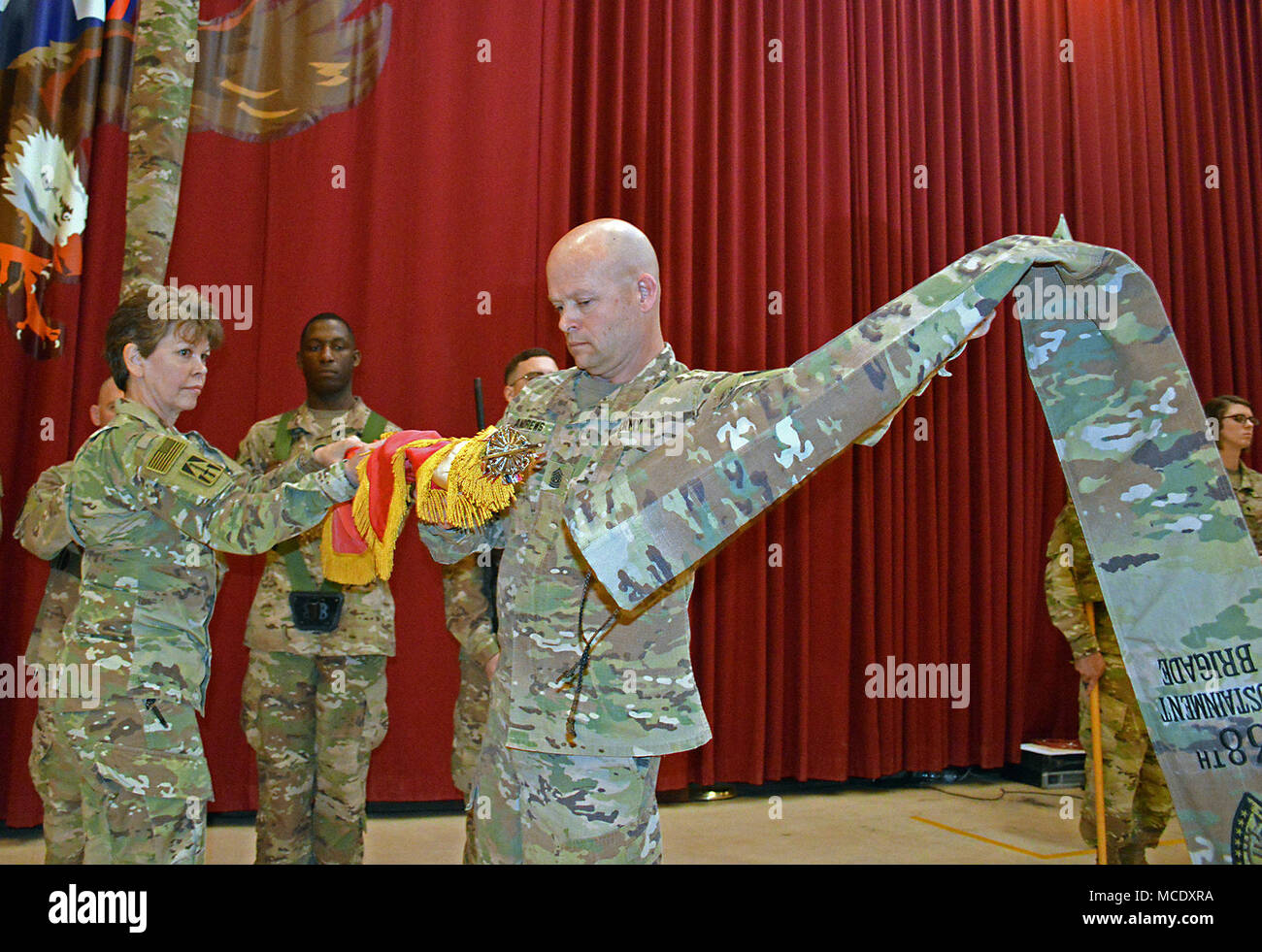 Oberst Kimberly Martindale, Kommandeur der 38. Der Indiana National Guard Sustainment Brigade, hält die Feuerwehr Farben mit Cpl. Devin McElveen Befehl als Sgt. Maj. Scott Andrews, brigade Senior Berater angeworben, zieht die Abdeckung während der Entfaltung der Farben teil der Übertragung der Autorität Festakt im Camp Arifjan, Kuwait, am 13.02.26. Die Brigade empfangene Befehl und Kontrolle von der 371 Sustainment Brigade. (Foto durch Master Sgt. Brad Staggs, 38th Sus. Bde. Public Affairs) Stockfoto