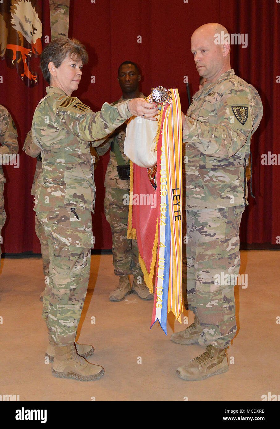 Cpl. Devin McElveen, hält die 38th Sustainment Brigade Farben als Oberst Kimberly Martindale, Kommandant der 38th, und Command Sgt. Maj. Scott Andrews, brigade Senior Berater angeworben, entfalten die Farben während einer Übertragung der Autorität Festakt im Camp Arifjan, Kuwait, am 13.02.26. Die Brigade empfangene Befehl und Kontrolle von der 371 Sustainment Brigade. (Foto durch Master Sgt. Brad Staggs, 38th Sus. Bde. Public Affairs) Stockfoto