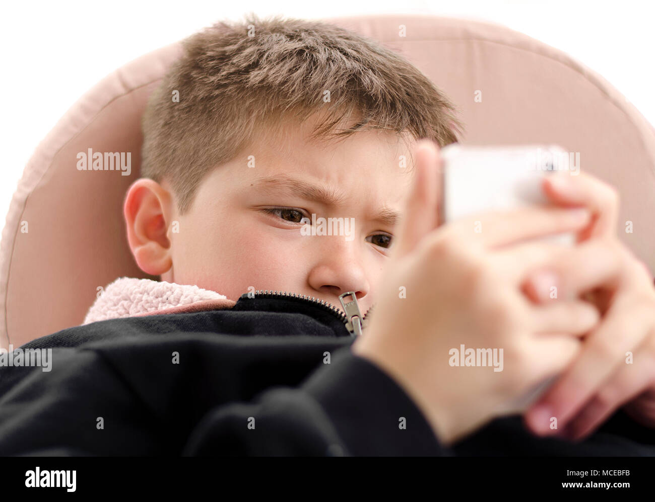 Vollständig absorbiert kleine Junge spielt mit Handy online Spiele. Auf weissem Hintergrund. Stockfoto