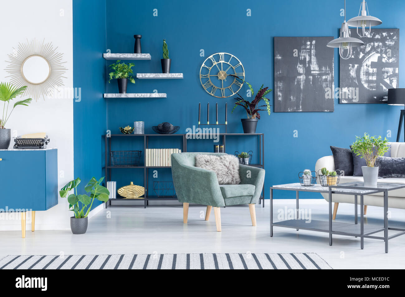 Schwarze Gemälde auf blauen Wand in der modernen Wohnzimmer Einrichtung mit grünen Sessel und Pflanzen Stockfoto