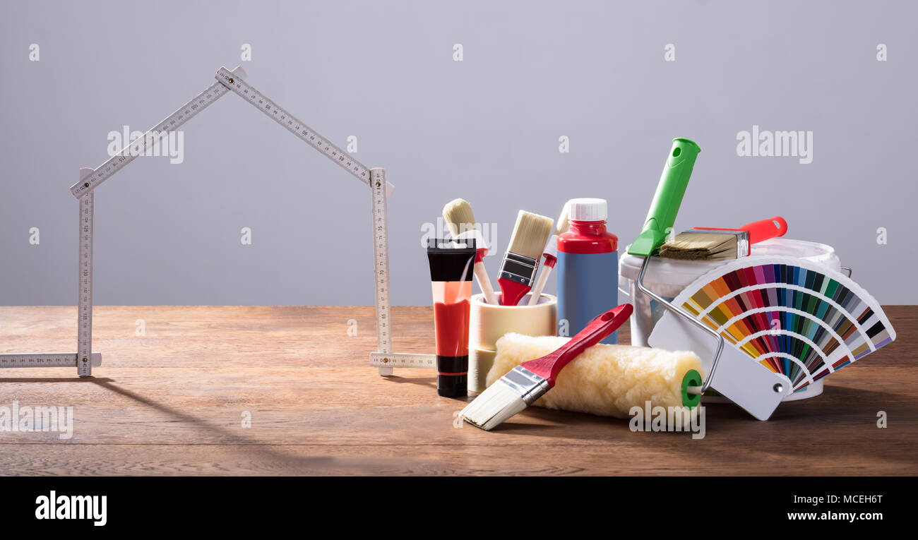 Messung House Band mit verschiedenen Malerei Ausrüstungen auf dem hölzernen Tisch gegen den grauen Hintergrund Stockfoto