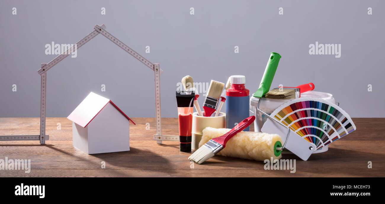 Messung House Band mit verschiedenen Malerei Ausrüstungen auf dem hölzernen Tisch gegen den grauen Hintergrund Stockfoto