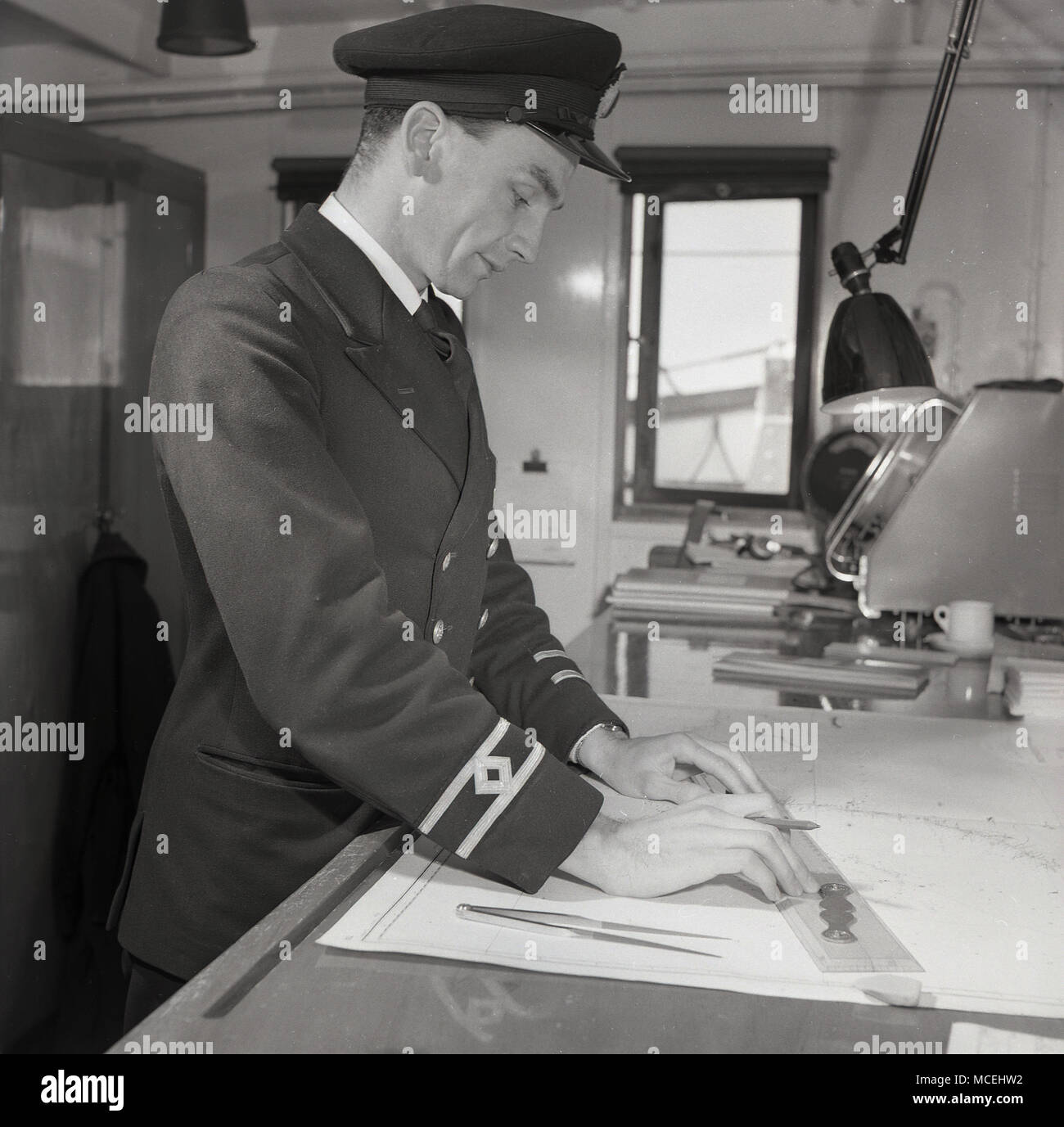 1950, historische, Zweiter Offizier oder den Navigator in seine Uniform an Bord das Deck eines Dampfers, der an den schifffahrtskarten genaue Position des Schiffes zu etablieren. Stockfoto