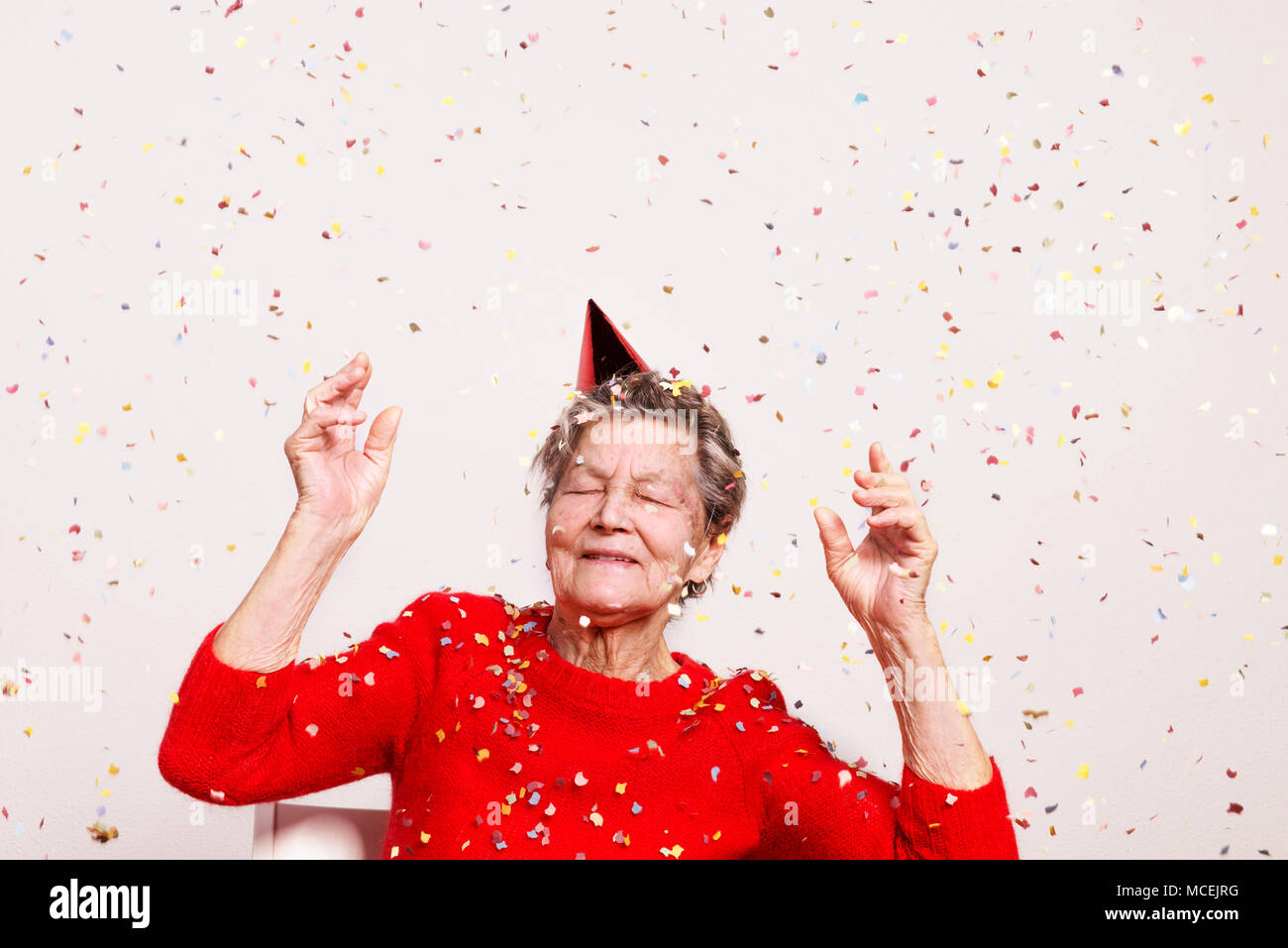 Porträt einer älteren Frau in Studio auf einem grauen Hintergrund. Party Konzept. Stockfoto