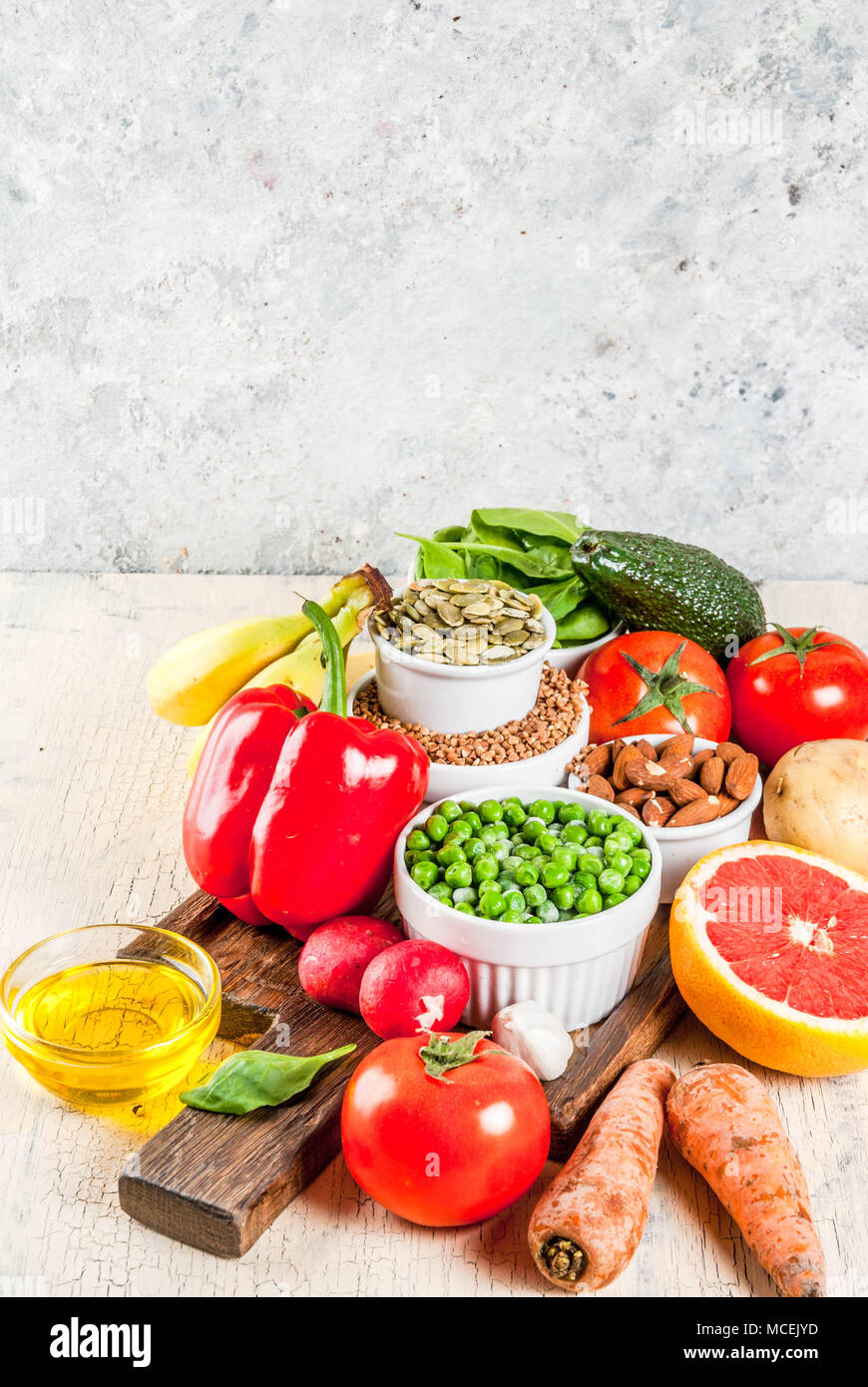 Gesundes essen Hintergrund, trendige Basische Ernährung Produkte - Obst, Gemüse, Getreide, Nüsse. Öle, Licht konkreten Hintergrund Kopie Raum Stockfoto