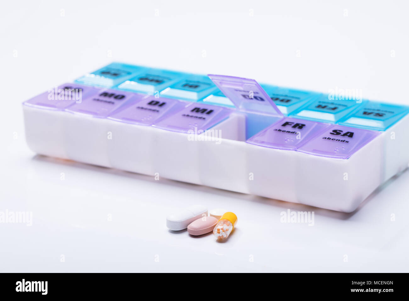 Rosa Kunststoff Pille Veranstalter geschossen und medizinische Pillen auf weißem Hintergrund Stockfoto