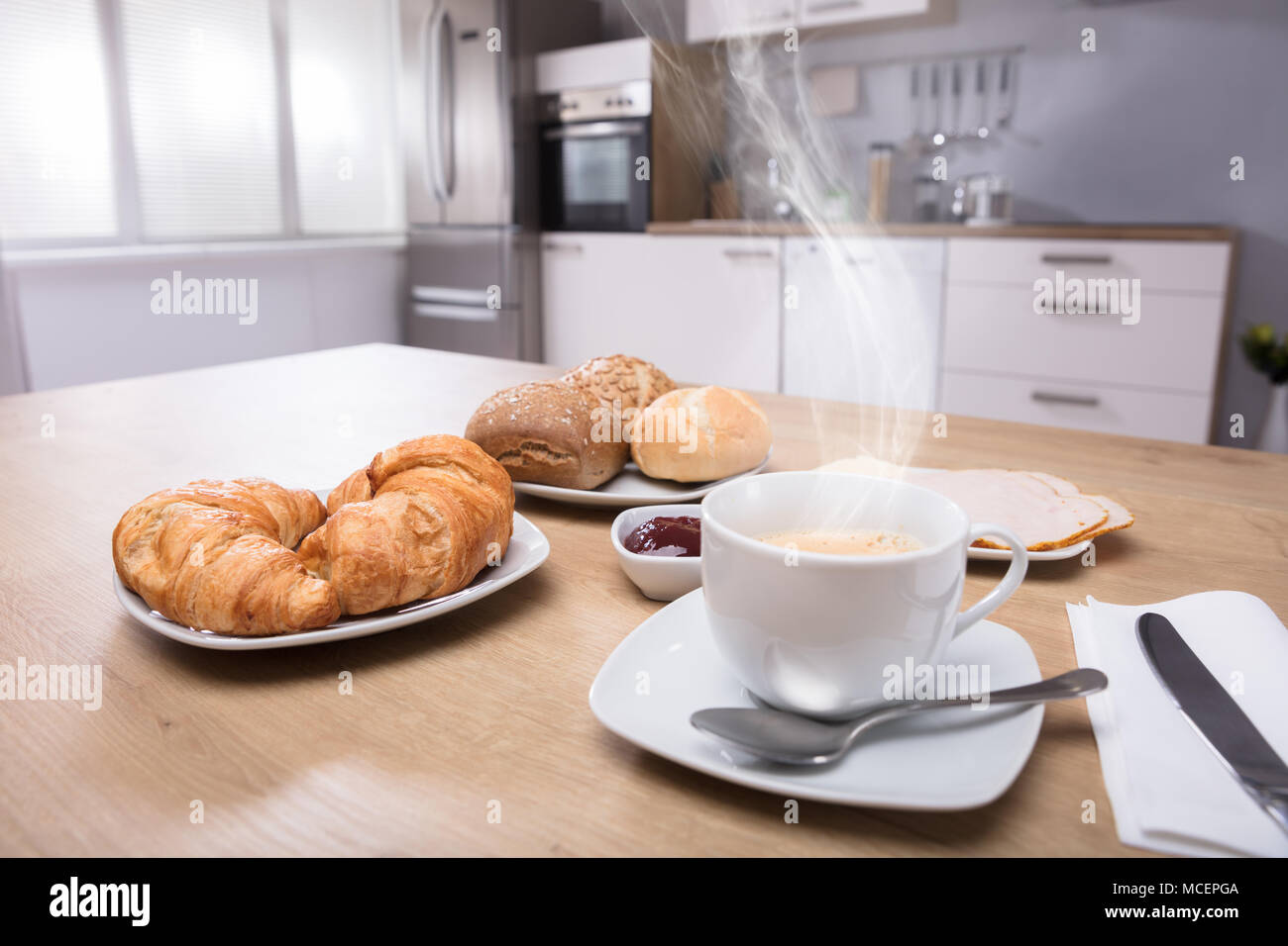 In der Nähe von Croissants und heiße Tasse Kaffee auf hölzernen Schreibtisch Stockfoto