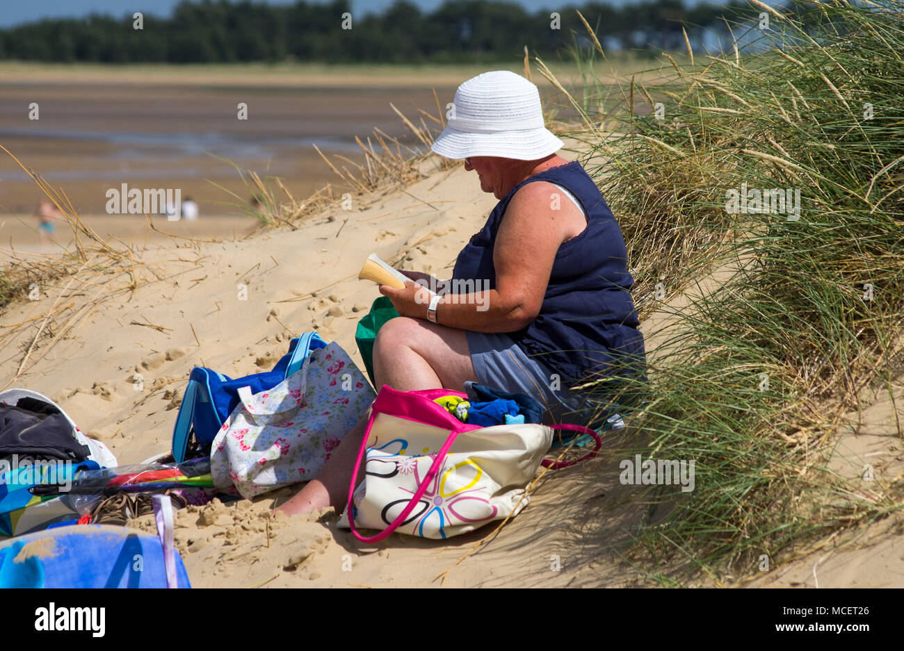 Eine Frau auf einer Düne mit einem Buch sitzen Stockfoto