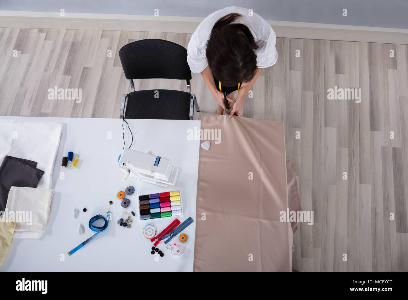 Junge weibliche Mode Designer Schneiden Tuch mit der Schere auf dem Schreibtisch im Studio Stockfoto