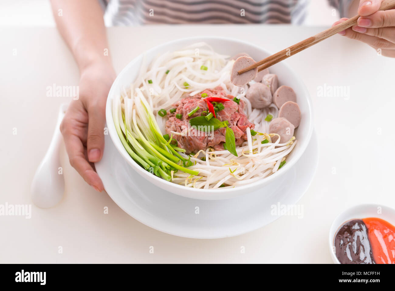 Frau essen traditionellen vietnamesischen Pho Nudeln mit Stäbchen. Stockfoto