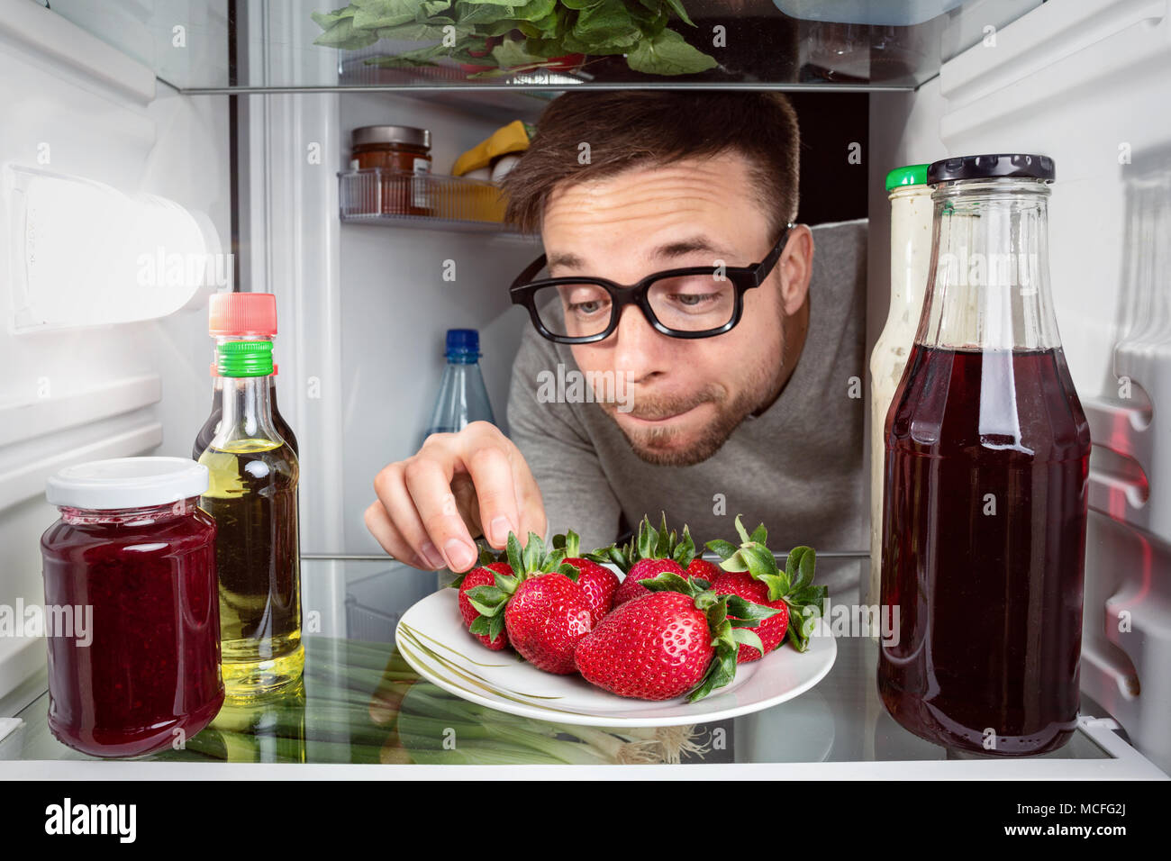 Mann erreichen für frische Erdbeeren im Kühlschrank Stockfoto