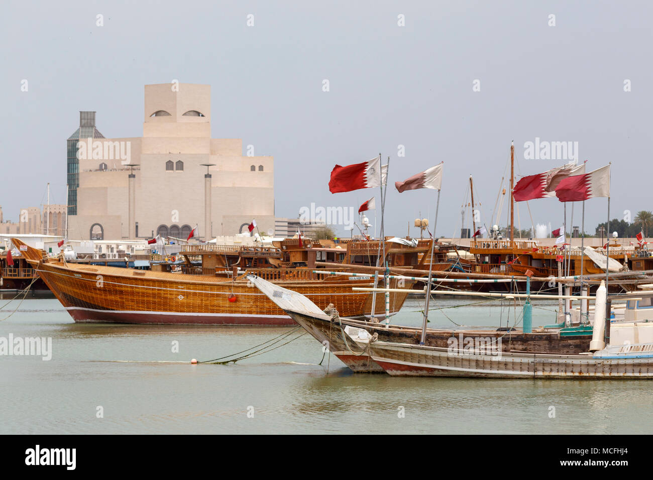 DOHA, Katar - 16. April 2018: Verschiedene traditionelle Holzboote fliegen die Katarische Fahne vor der Sehenswürdigkeit Museum für Islamische Kunst Stockfoto