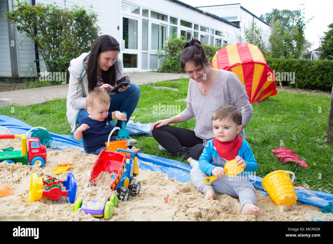 Babys spielen in einem Sandkasten Stockfoto