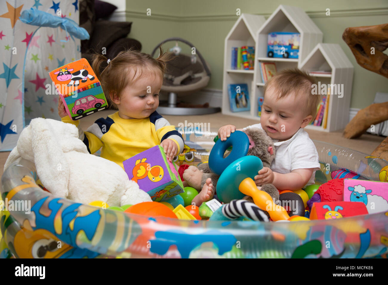 Babys, die mit ihren Spielsachen spielen. Stockfoto