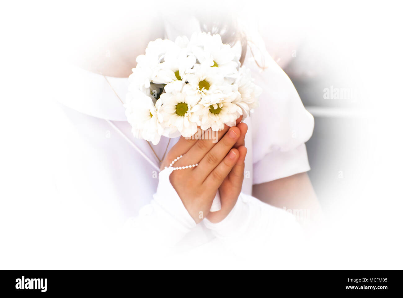 Mädchen in weißem Kleid Blumen halten auf die erste heilige Kommunion. Stockfoto