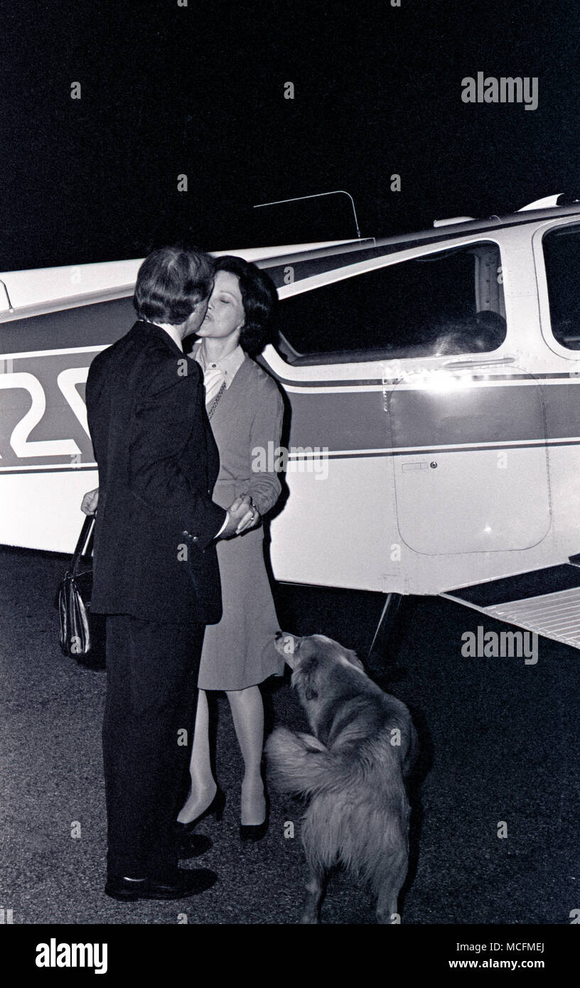 Eine Umarmung und ein Gruß von der Flughafen als Jimmy Carter trifft kleine Rosalynn's Flugzeug um Mitternacht nach einem Tag der Kampagne. Das Paar würde manchmal bis zu Leinwand split zweimal das Gebiet während der primärfarben. Im Gegensatz zu der heutigen Kandidaten, die frugal Carter verwendet ein kleines Flugzeug früh in seiner 1975 - 1976 Presidential Campaign. Stockfoto