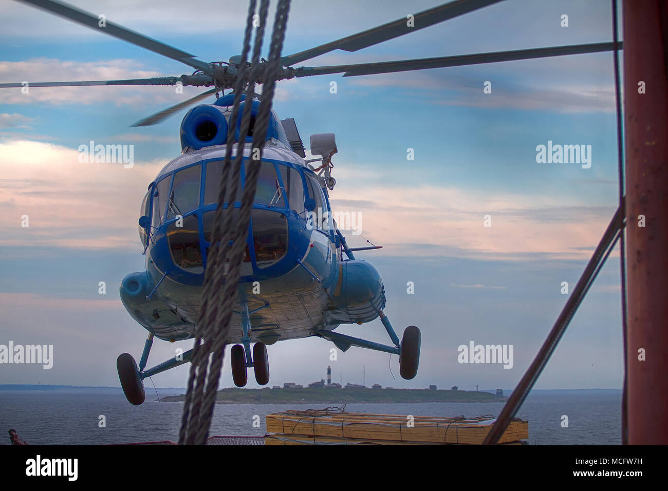 Schiff Hubschrauber, Landung auf dem Landeplatz am Heck des Schiffes, auf dem Hintergrund der Insel und Leuchtturm, Be- und Entladen. Hubschrauber macht Eis Stockfoto