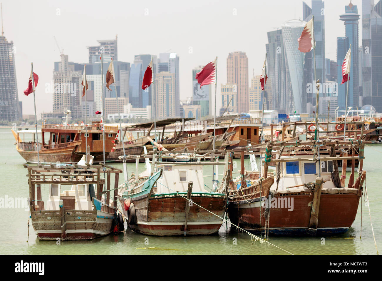 DOHA, Katar - April 15, 2018: Kleine Fischerboote flying qatari Flaggen in den Hafen mit Türmen hinter sich. Zeigt der Loyalität haben seit Katar w erhöht Stockfoto