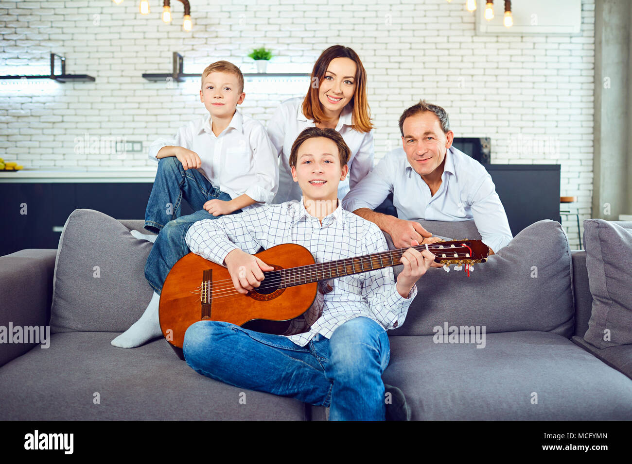 Glückliche Familie mit Gitarre Lieder singen im Zimmer sitzen  Stockfotografie - Alamy