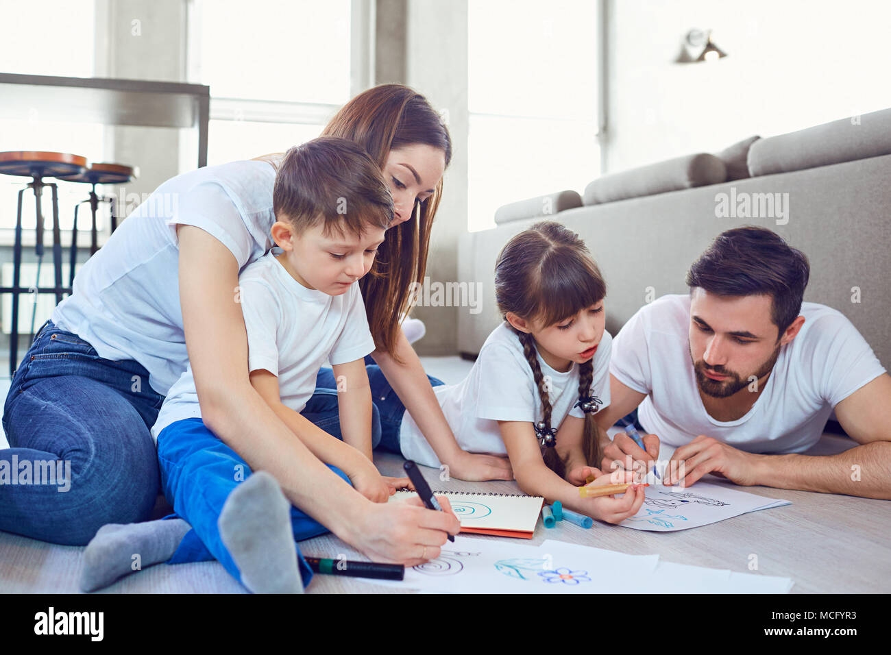 Eine Familie zieht auf dem Papier liegen auf ihre freie Zeit auf dem Boden im Zimmer. Stockfoto
