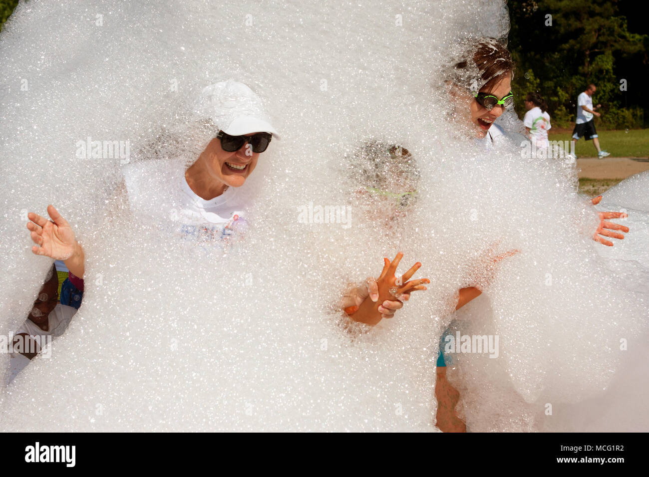 Lawrenceville, GA, USA - 31. Mai 2014: Frauen lächeln und lachen, während sich aus einer Wolke von Schäumenden Seifenlauge auf Bubble Palooza. Stockfoto