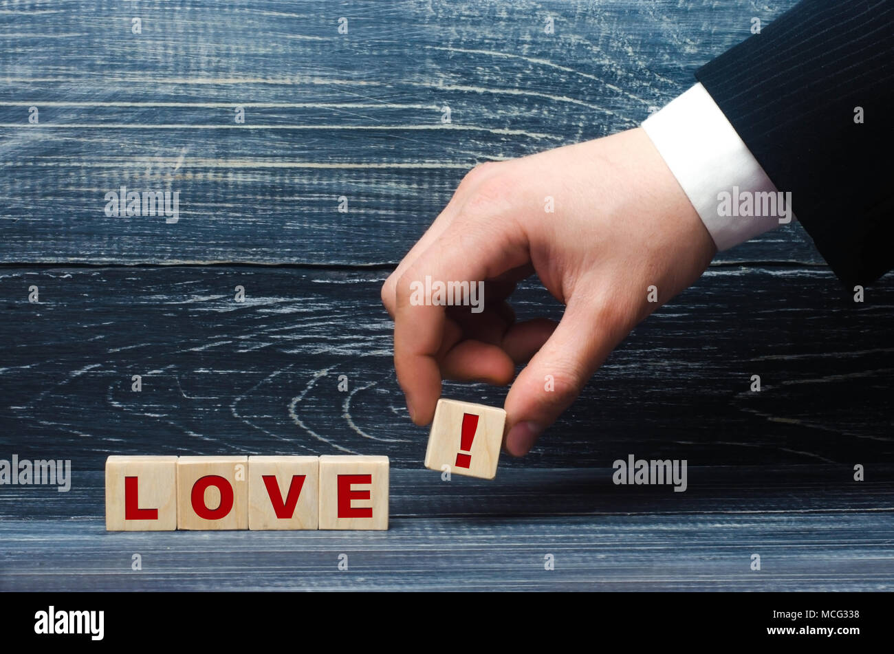 Hand hält einen Würfel mit dem Symbol der ein Ausrufezeichen auf das Wort Liebe. Das Konzept der Liebe, und die Liebe Beziehungen, Loyalität und Gefühle. Junge co Stockfoto