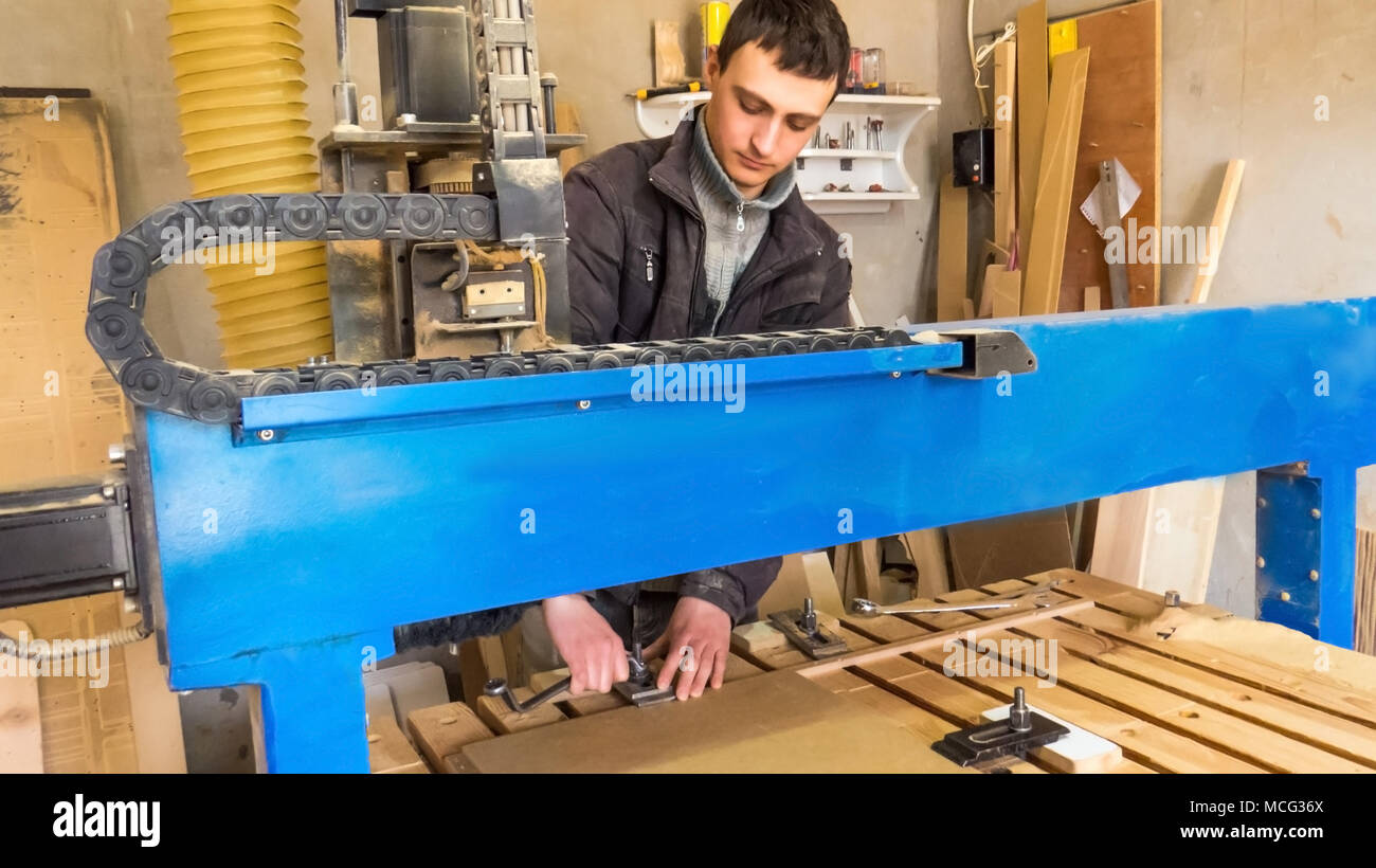 Der Arbeitnehmer Wendungen der Überwurfmutter an der CNC-Maschine. CNC-Fräsmaschine, Verarbeitung von Holz. Tischlerei, Möbel und Produkte aus Holz. Wartung Stockfoto