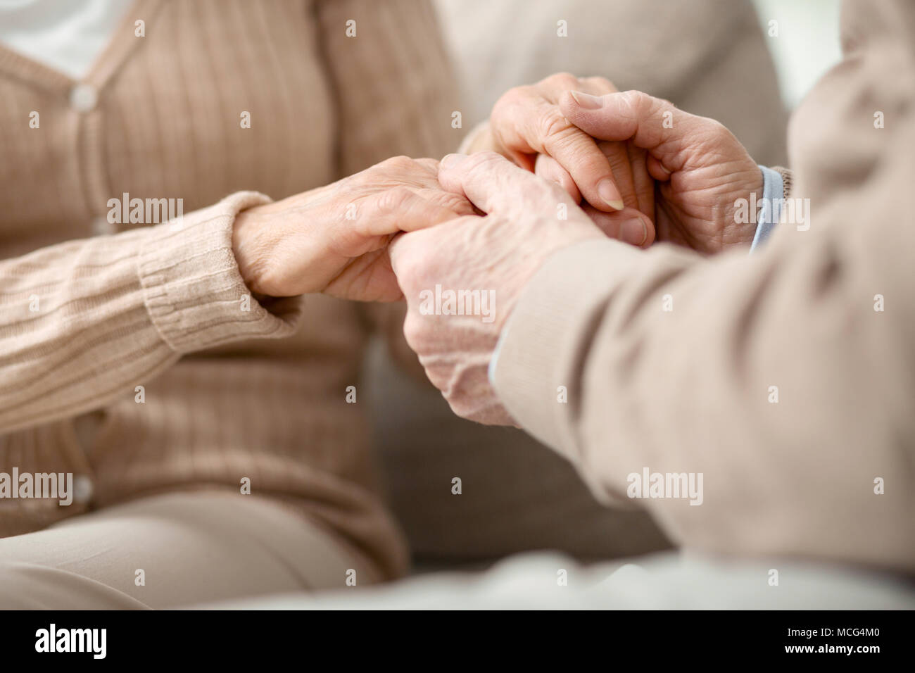 Schönes alter Mann halten sich an den Händen seiner Frau Stockfoto