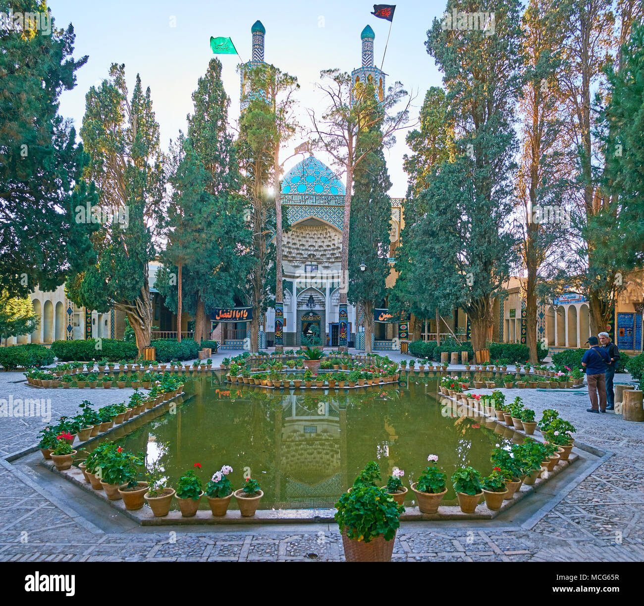 MAHAN, IRAN - Oktober 16, 2017: Die malerische Vakil-ol-molki Innenhof von Shah Nematollah Vali Schrein mit üppigen Nadelwälder Garten, polygonalen Teich und Tur Stockfoto