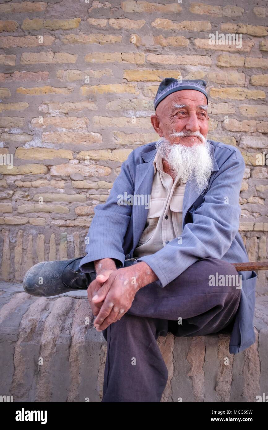 Man saß ruhig auf der Straße Ecke in der lebendigen Stadt Chiwa, Usbekistan. Sein Gesicht zeigt die Jahre der Wandel in Zentralasien gesehen hat. Stockfoto