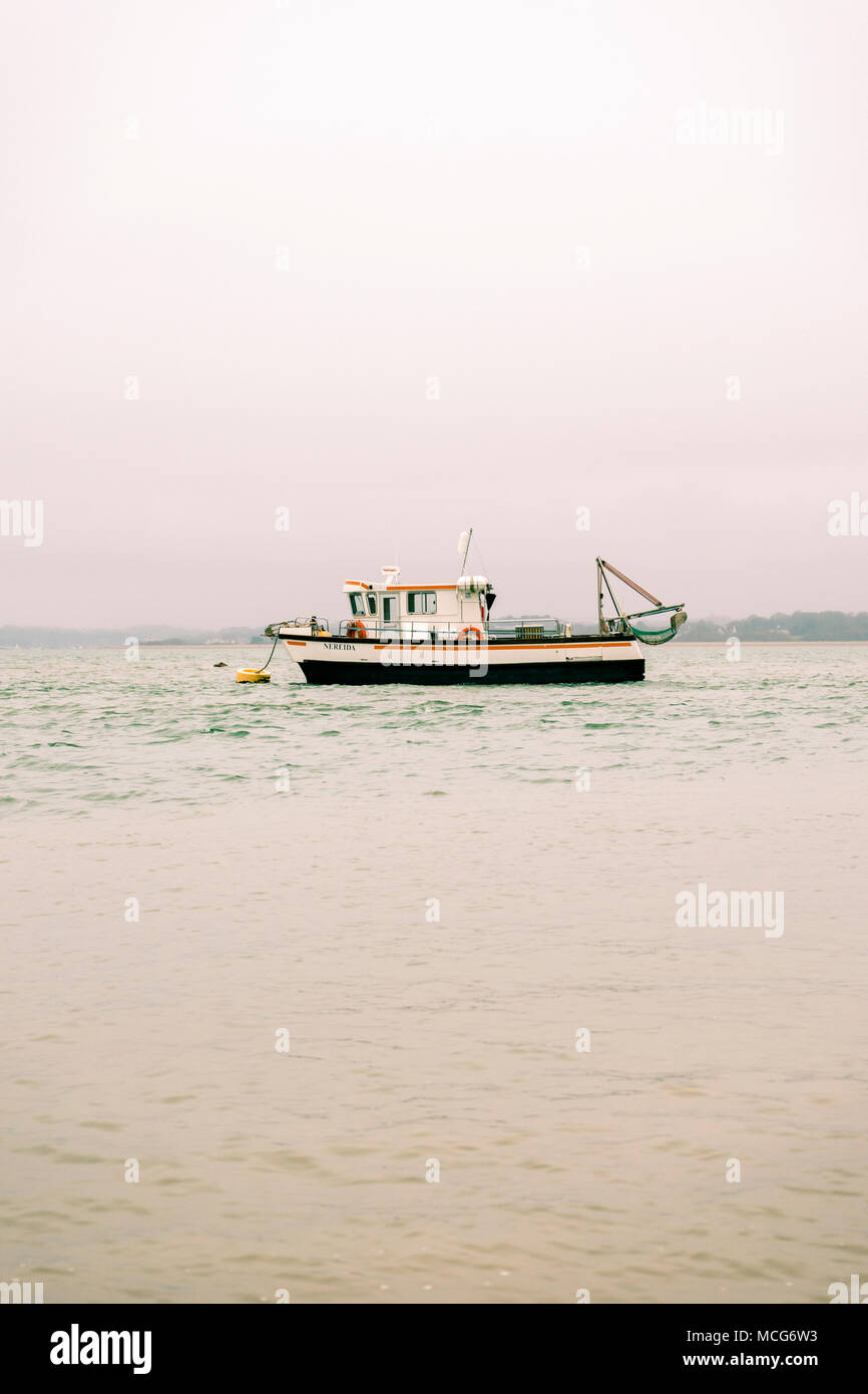 Ein leeres Fischtrawler / Fischerboot in der Solent in der Nähe von Calshot an einem nebligen bewölkten Tag, Split getönten, England, Großbritannien Stockfoto