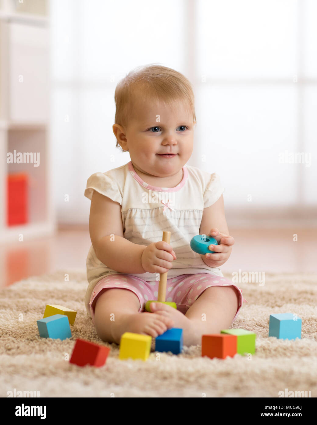 Adorable Baby spielt mit bunten Spielzeug Pyramide sitzen