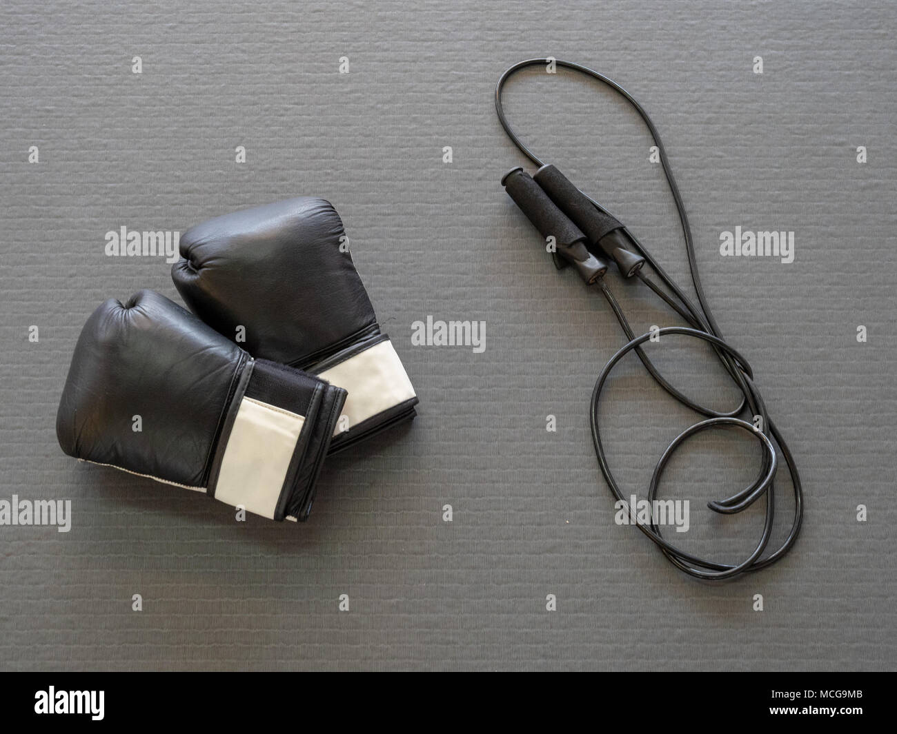 Schwarze Boxhandschuhe und springen Seil auf der Gymnastikmatte, für Kreuz bereit - Schulung Stockfoto
