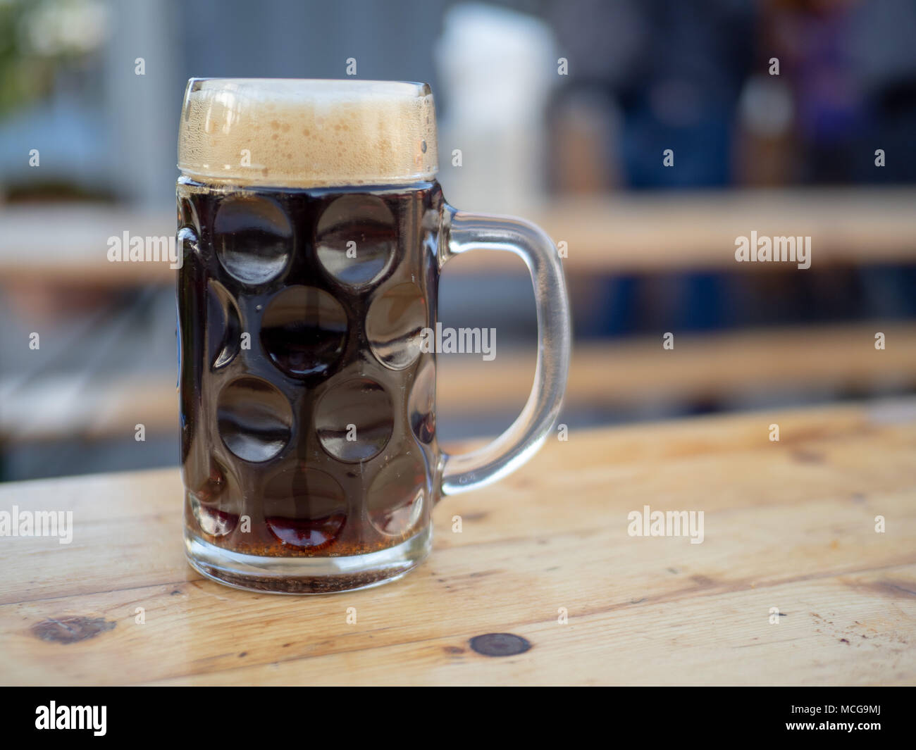 Deutsche Glas Bierkrug mit einem dunklen ale sitzen auf hölzernen Tisch gefüllt Stockfoto