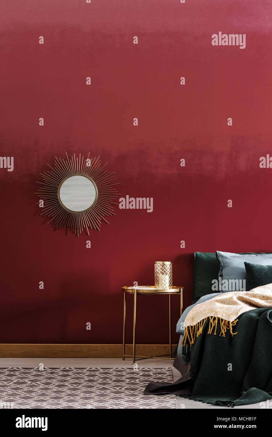 Golden, dekorativ, runden Spiegel hängt ein Burgunder Wand im Schlafzimmer Innenraum Stockfoto