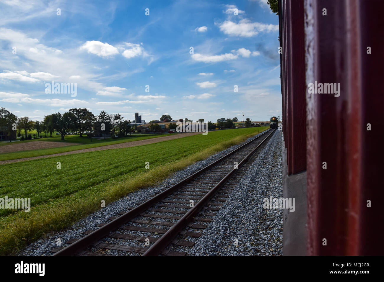 Züge, die einander auf der anderen Spur in Amish Landschaft an einem sonnigen Tag mit blauen Himmel Stockfoto