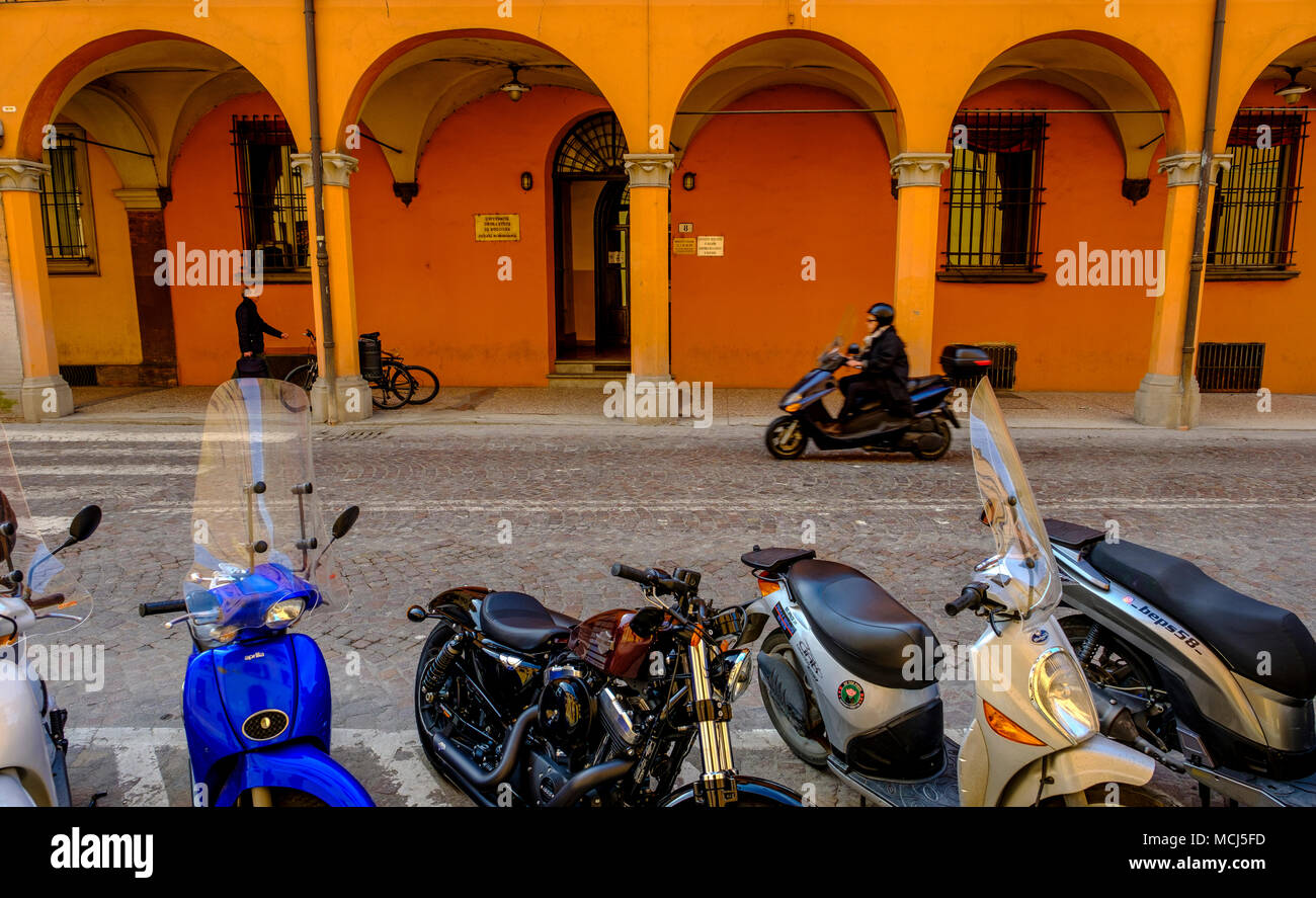 Ein Mann auf einem Moped Geschwindigkeit entlang einer Straße in Bologna, Italien Stockfoto