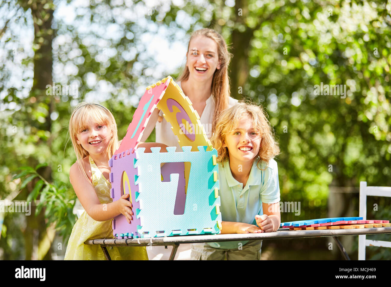 Glückliche Mutter und Kinder freuen sich über Ihre kreativen Traum Haus puzzle Stockfoto