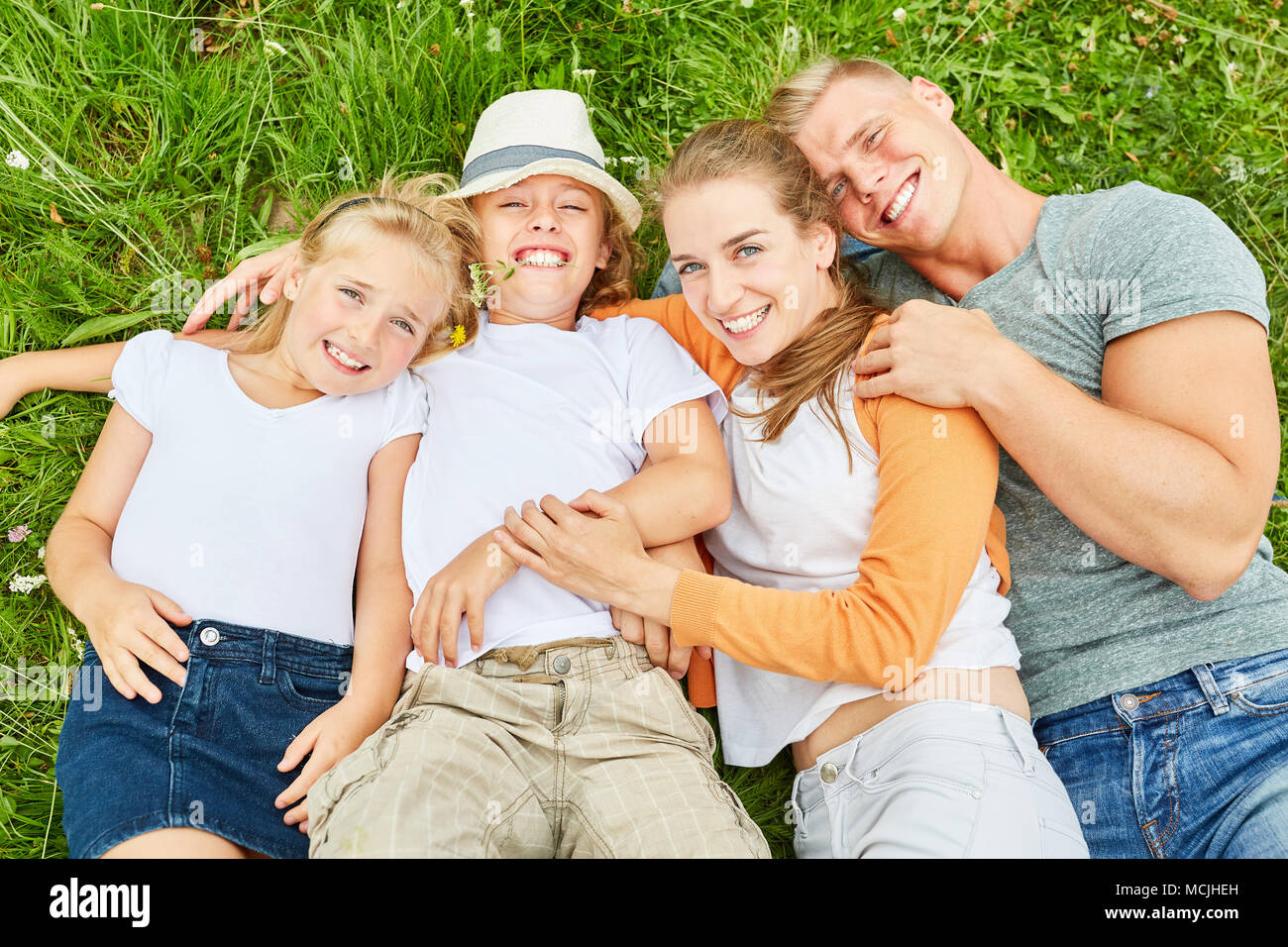 Glückliche Familie und zwei Kindern liegen im Garten entspannt Stockfoto