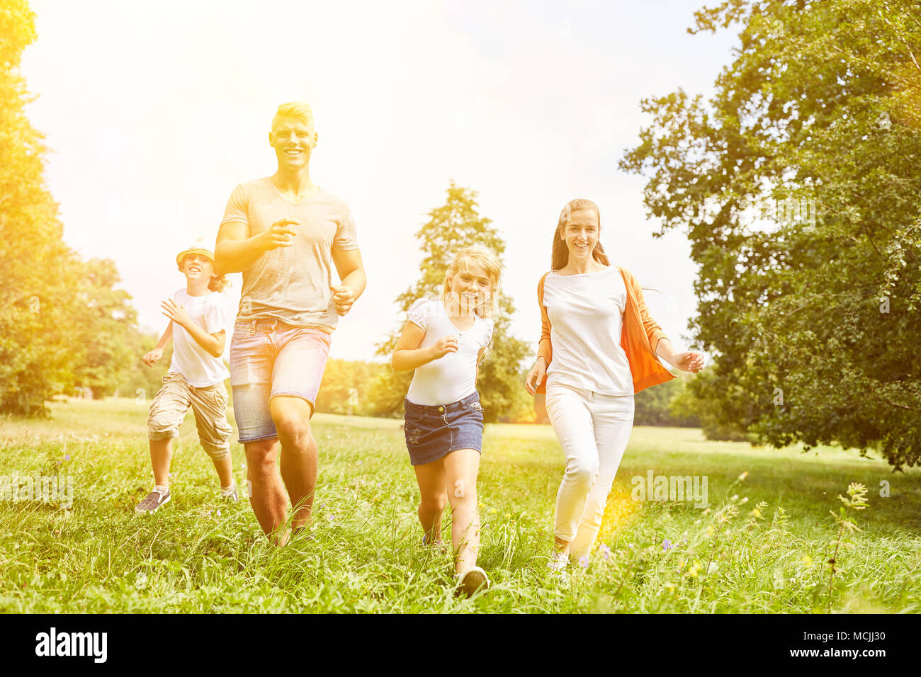 Happy Family und Kids Run zusammen als Sport über einer Wiese im Sommer Stockfoto