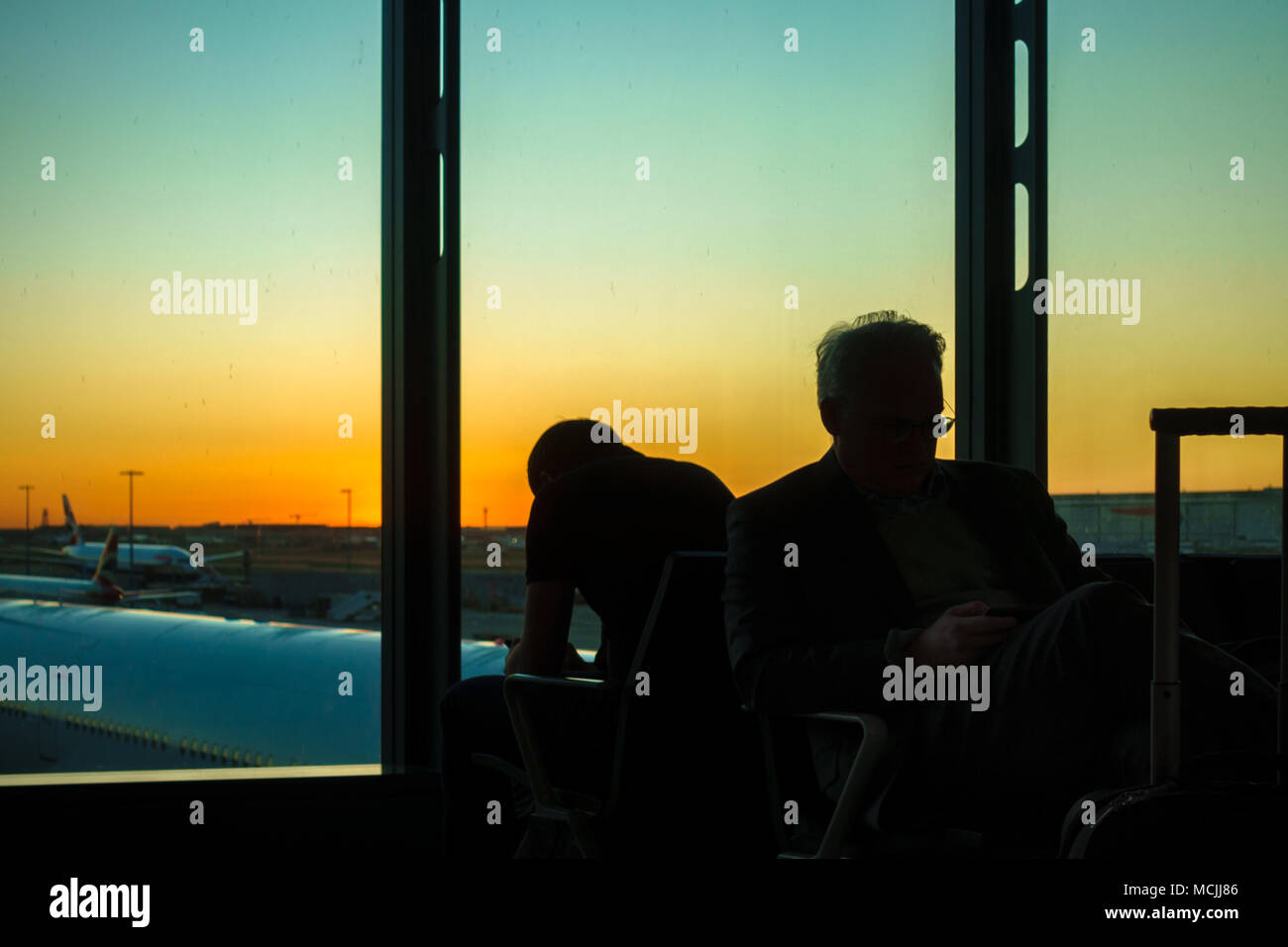 Silhouette von zwei Männern, die auf dem Airport Terminal in der Dämmerung, Athen, Griechenland Stockfoto