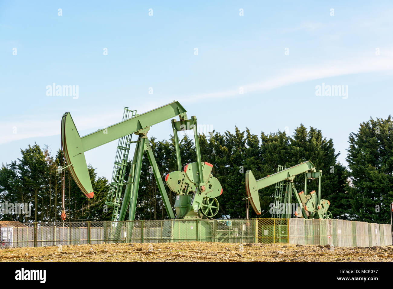 Zwei aktive pumpjacks Öl pumpen aus einer gut befindet sich im Zentrum von Frankreich unter einem blauen Himmel. Stockfoto